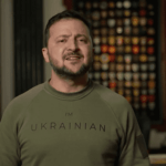 A man stands in front of a wall adorned with emblems, wearing a green shirt that says "I'm Ukrainian." A Ukrainian flag, symbolizing support in the struggle against Russia, is visible to the left. A lamp sits to the right. The image bears a YouTube watermark in the lower right corner.