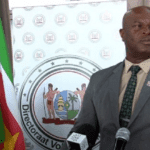Man spreekt op persconferentie met Surinaamse vlag