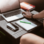 Persoon werkt buiten met laptop en notities